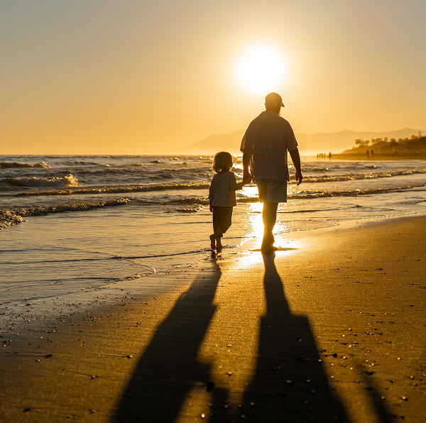 a father and daughter walking on the beach