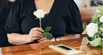 a woman laying down a white rose on a coffin
